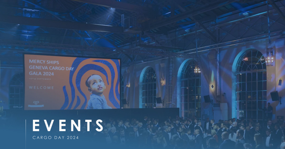Gala crowd in an industrial hall before a screen reading Mercy Ships Geneva Cargo Day Gala 2024