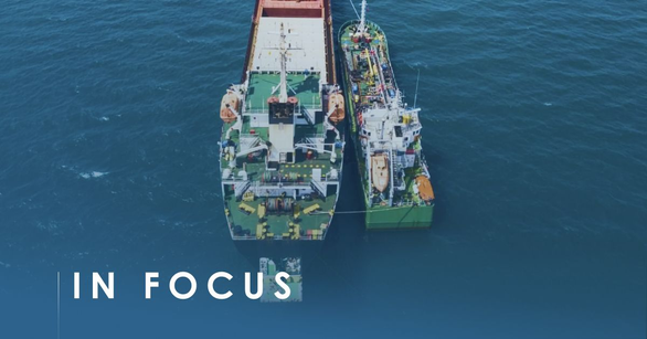 Small green bunker tanker moored alongside a larger cargo ship at sea, seen from above