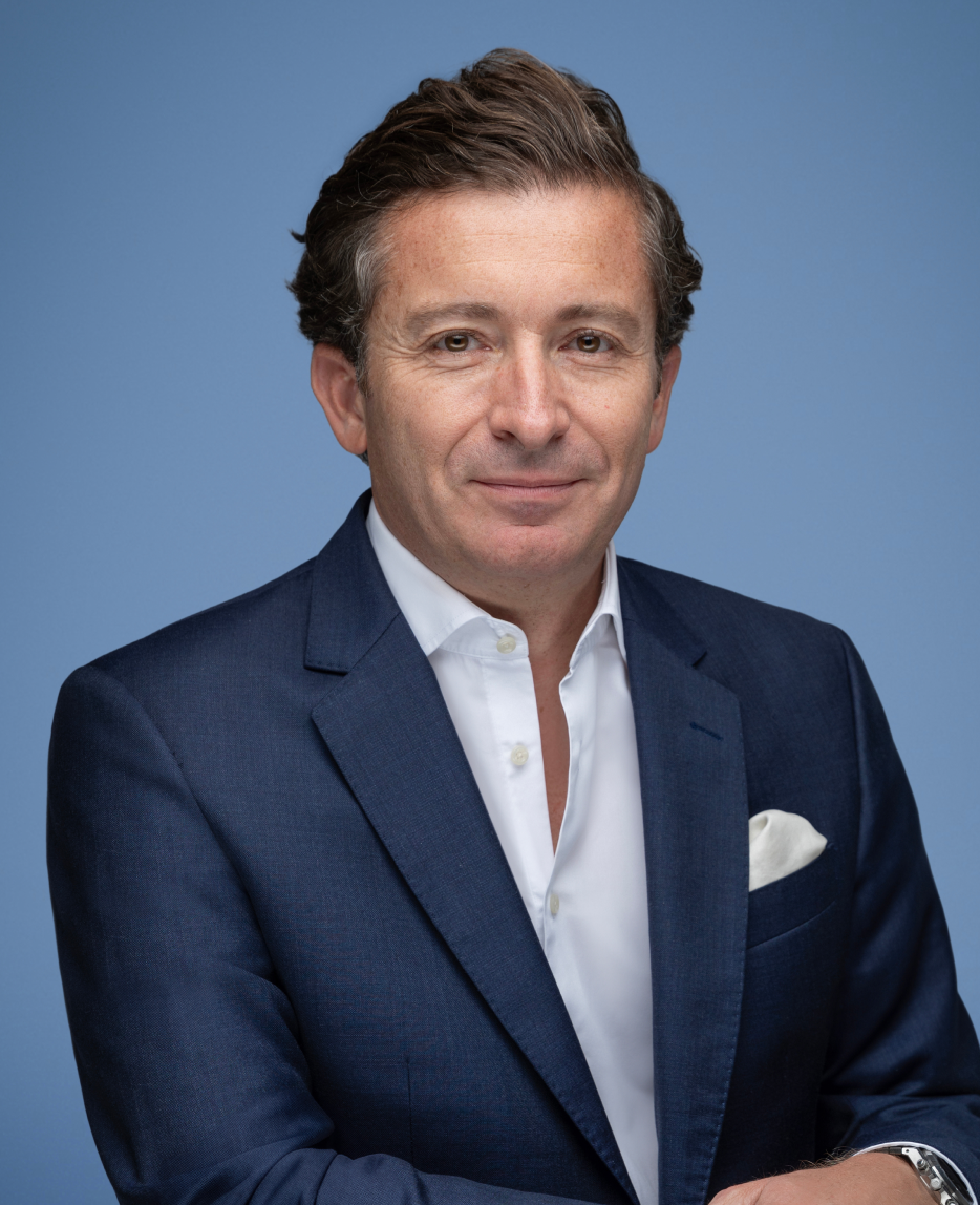 Yannick Luce, Meridor Group CFO, in a navy suit and white shirt on a blue backdrop